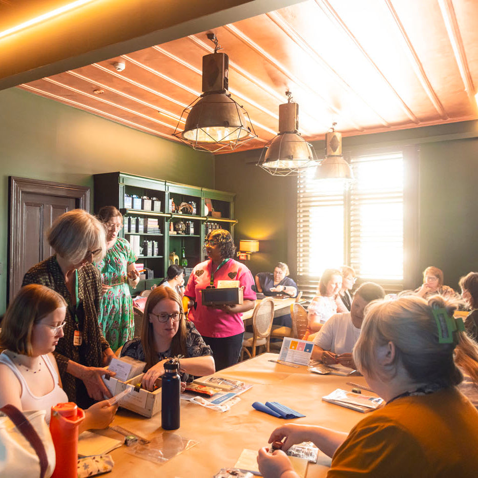 People gathered around a table for a creative stationery workshop in a cozy room with wooden beams and green walls.